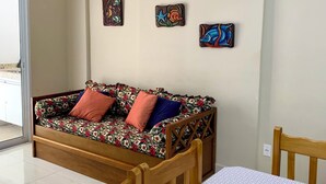 Una habitación con un sofá de madera, una mesa de comedor y un ventilador de techo.