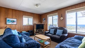 Uma sala de estar acolhedora com paredes de madeira, uma televisão grande e assentos confortáveis.