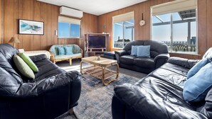 Sala de estar com sofás de couro, televisão e uma janela grande com vista.