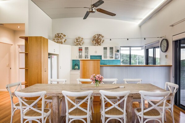 A modern kitchen with white cabinets, a wooden island, and a dining area with white chairs.