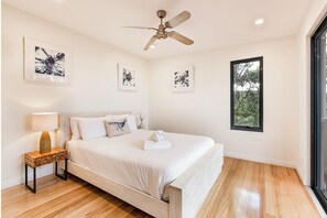 A bedroom with a bed, a ceiling fan, and artwork on the walls.