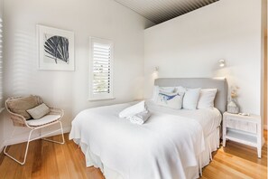 Ein Schlafzimmer mit einem Bett, einem Sessel, einem Nachttisch und einem Wandbild.