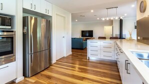 Een moderne keuken met roestvrijstalen apparatuur, houten vloeren en een centraal eiland met lades.
