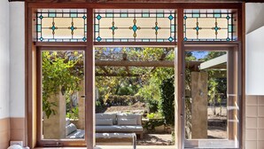 A kitchen with a built-in sink, a kettle, and a window with a view of a garden and outdoor seating. - The Bower House | Margaret River (Margaret River)