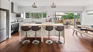 A modern kitchen with a central island, bar stools, and a dining table.