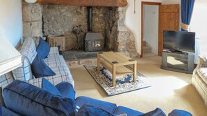 A cozy living room with a stone fireplace, a sofa set, a coffee table, and a television. - 5 bedroom accommodation in Horton, near Gower (Horton, near Gower)