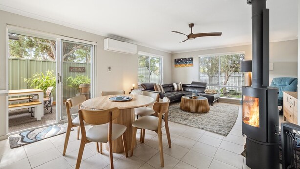 A modern living room with a fireplace, a dining area with a round table and chairs, and a sofa set.