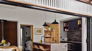 Une cuisine moderne dotée d’un îlot central, d’appareils électroménagers intégrés et d’un coin repas avec une table et des chaises en bois.