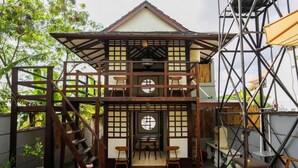 A traditional Japanese-style building with a two-story structure, wooden lattice walls, and tatami mat flooring. - Griya De Sachi (Cepaka)