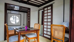 A traditional Japanese-style room with tatami flooring, a low wooden table, and two wooden chairs with cushions. - Griya De Sachi (Cepaka)
