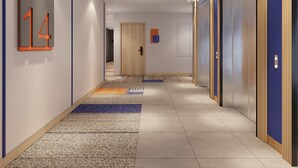 A modern hallway with a carpeted floor, a sign indicating the floor number, and a door at the end.