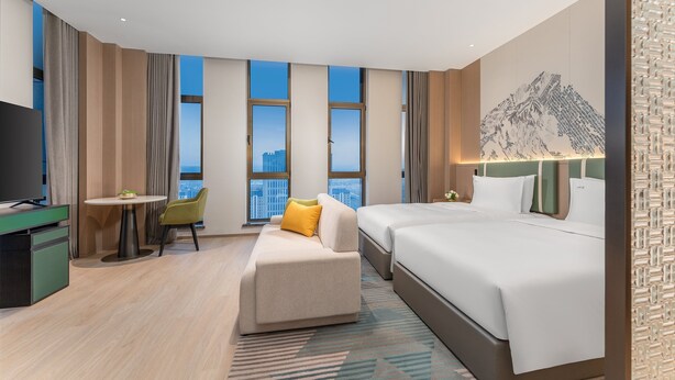Une chambre d’hôtel avec un lit, un bureau, une chaise, une petite table et un téléviseur.