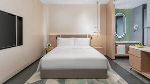 A modern hotel room with a large bed, bedside tables, a nightstand, a mirror, and a bathroom with a sink and mirror. - Holiday Inn Liaoyuan City Center by IHG (Liaoyuan)