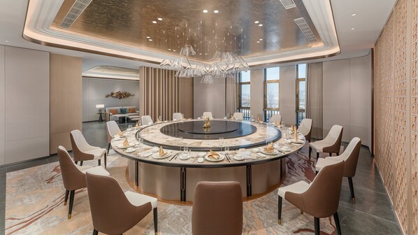 A modern conference room with a round table, comfortable seating, and a decorative chandelier. - Holiday Inn Liaoyuan City Center by IHG (Liaoyuan)