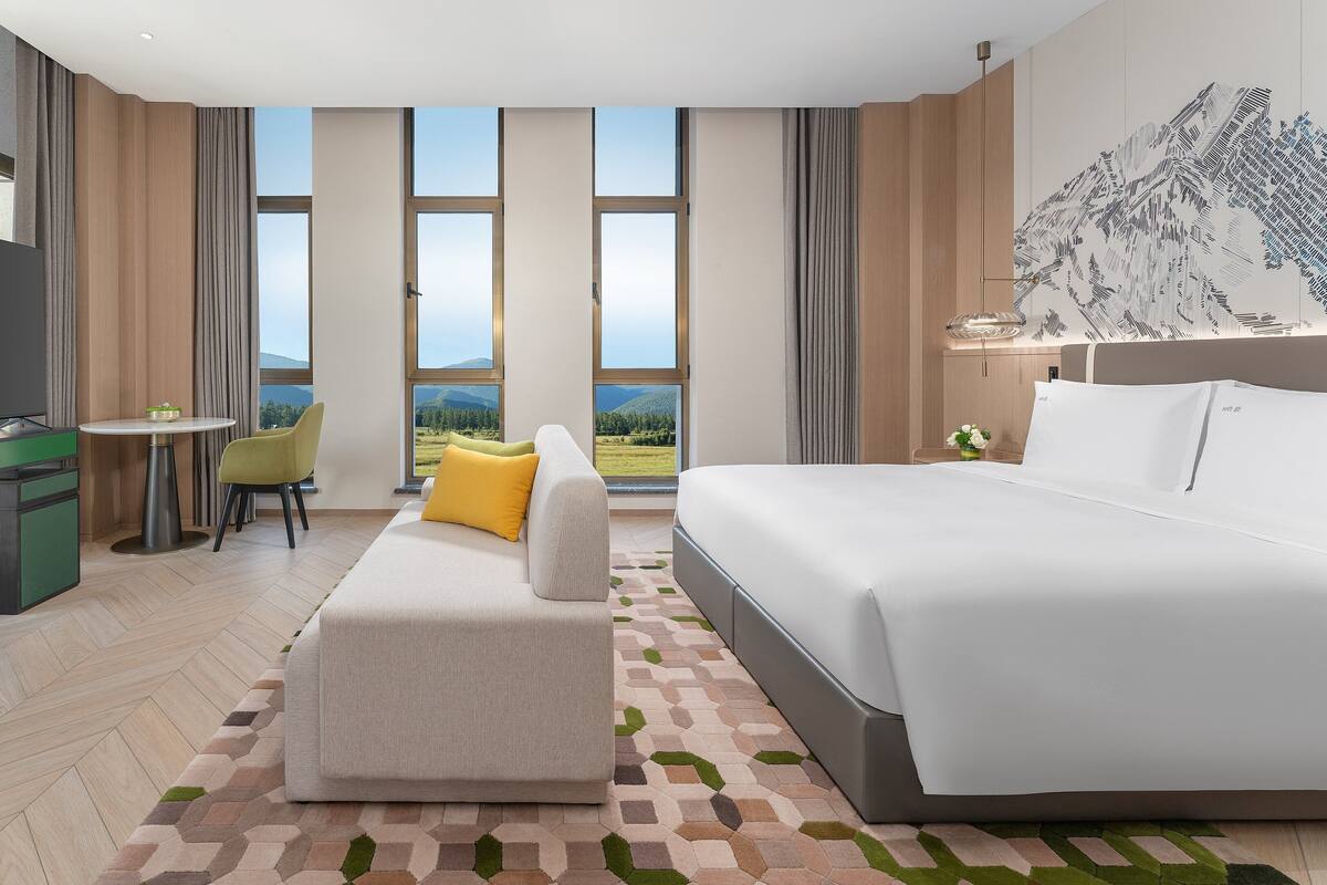 Une chambre d’hôtel moderne avec un grand lit, un bureau avec une chaise, un canapé et un téléviseur.