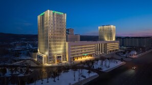 Un hotel moderno con un design verticale distintivo, ampie finestre e una facciata ben illuminata.