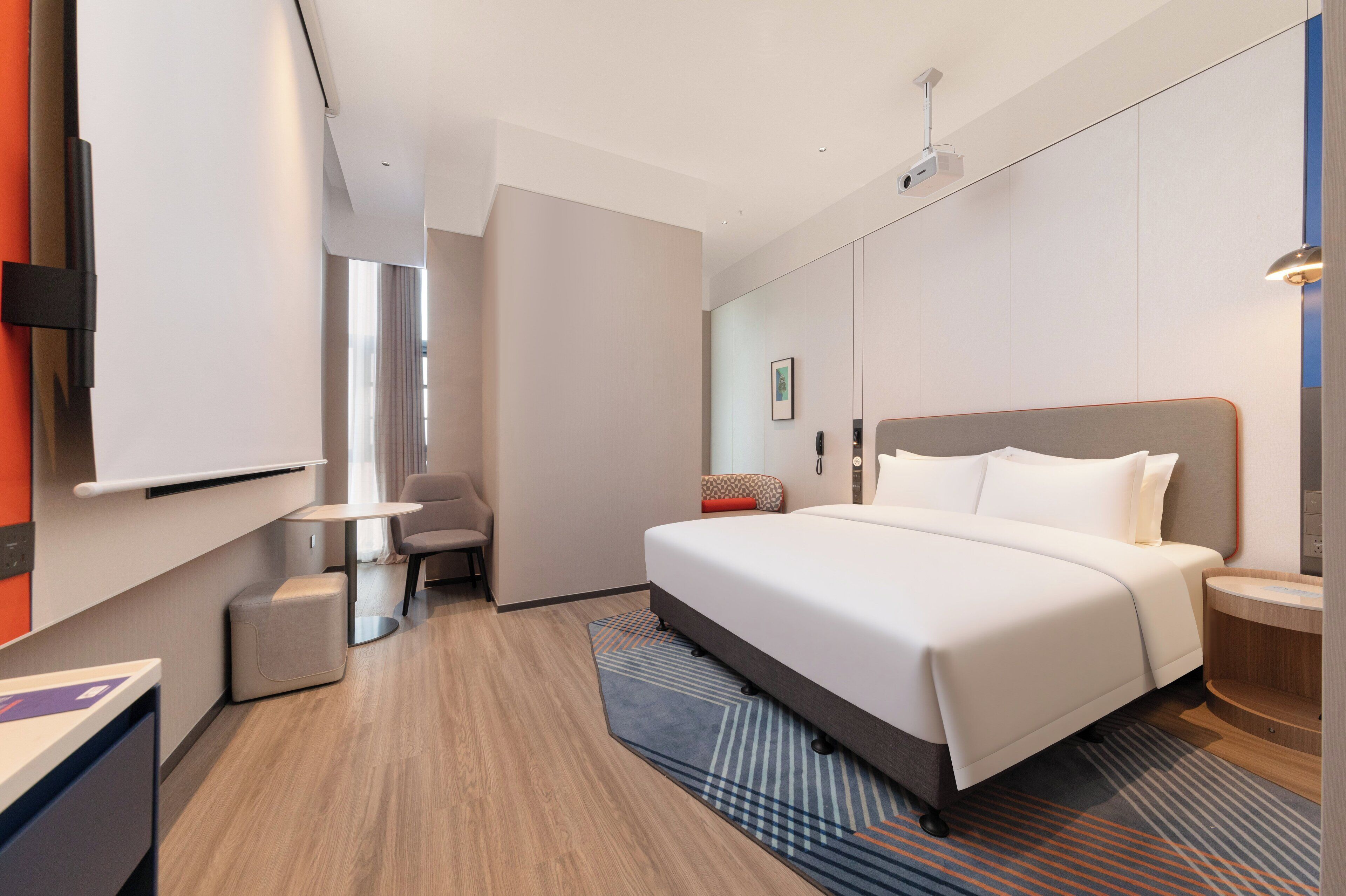 Une chambre d’hôtel moderne avec un grand lit, un bureau, une chaise et une petite table.