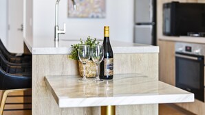 A modern kitchen with a marble countertop, a wine bottle, and two glasses. - Cozy 2 Bed 1 Bath Ocean/City View Unit(No Parking) (14013 - 5N - NB) (Broadbeach)