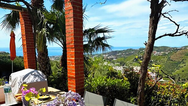 A table set outdoors with food and drinks, overlooking a scenic landscape.