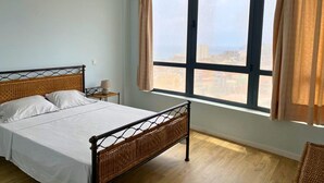 Un dormitorio con una cama, una mesita de noche, una lámpara y un ventanal con cortinas.