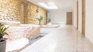 A corridor with stone walls, a skylight, and a potted plant. - Gardin home (Cali)