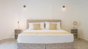 A neatly arranged bedroom with a large bed, two bedside tables, and a wall-mounted light fixture. - Gardin home (Cali)