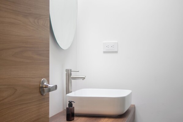 Un bagno con un lavandino bianco, una porta in legno e uno specchio.