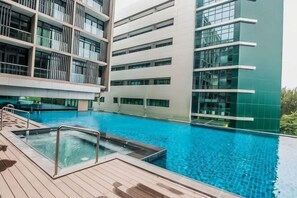 Un edificio moderno con piscina, ampie finestre e terrazza in legno.