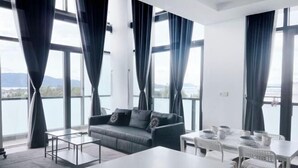 A modern room with a sofa, a dining table with chairs, and large windows with curtains. - Kwen Suites - City Centre Riverson Soho 2Br l Studio l Duplex (Kota Kinabalu)