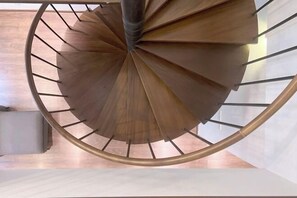 Un escalier en colimaçon avec une rampe métallique et des marches en bois.