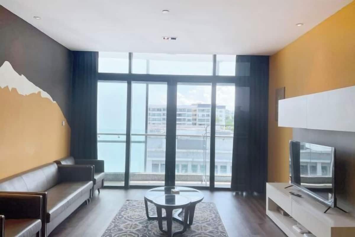 Ein modernes Hotelzimmer mit großem Fenster, einer Couch, einem kleinen Tisch und einem Fernseher.