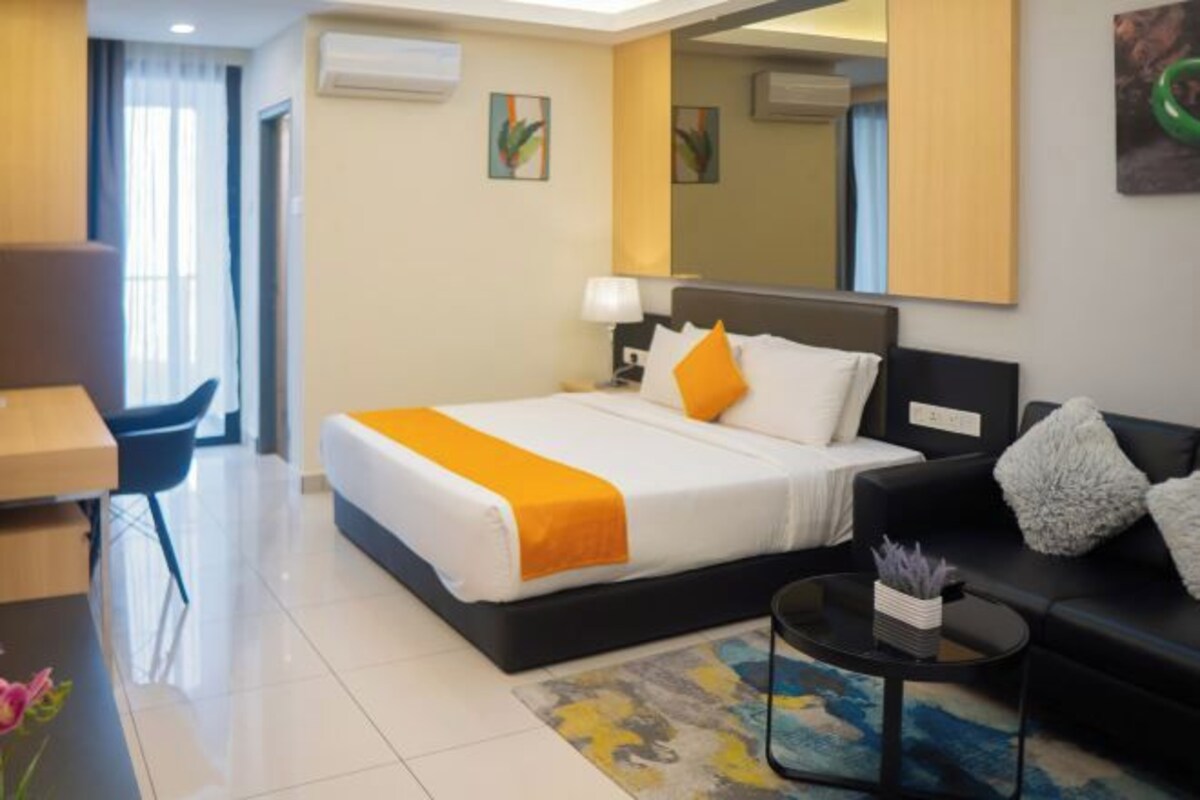 A hotel room with a bed, a desk, a sofa, a coffee table, and a mirror.