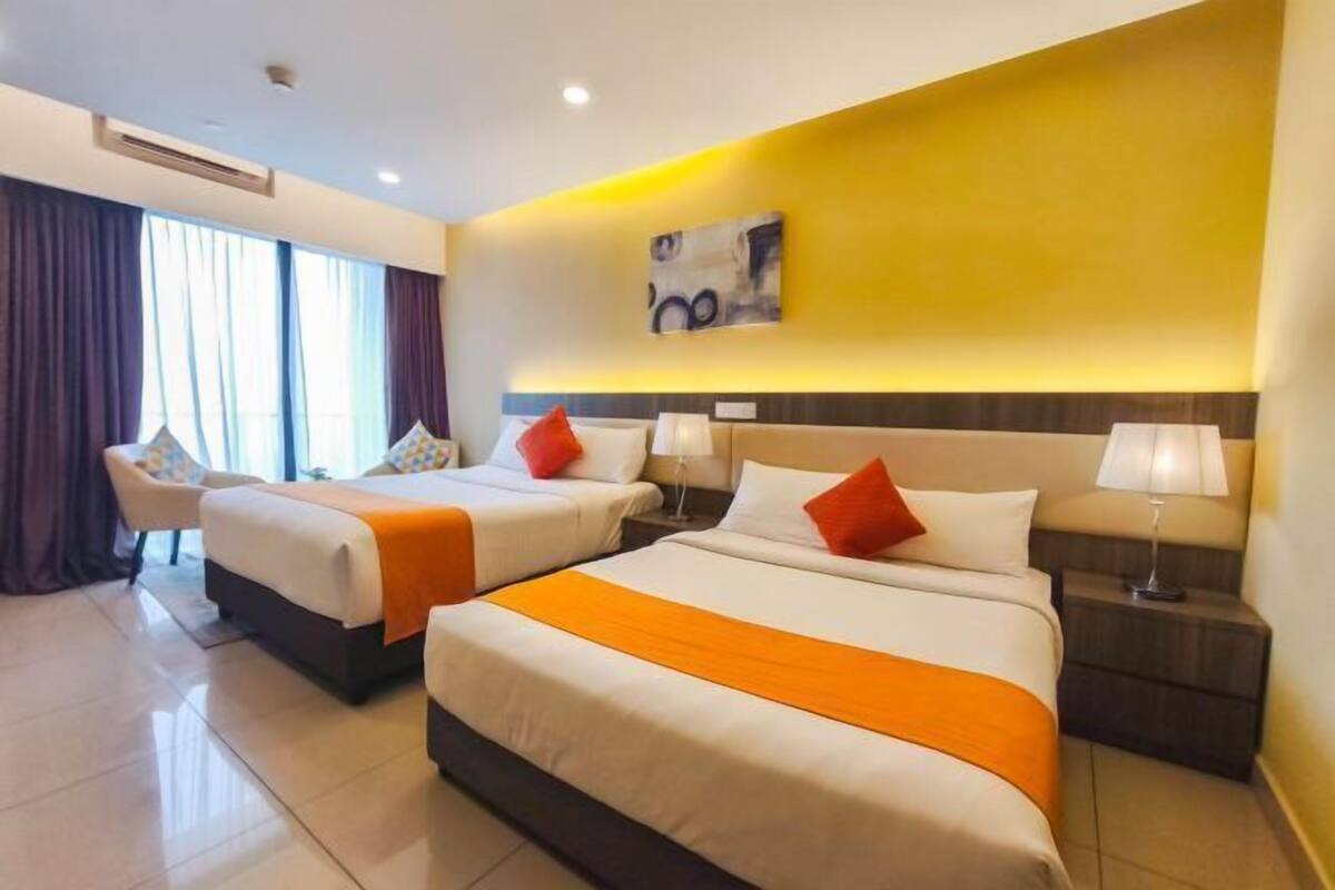 Una camera d'albergo con due letti, un divano e un comodino con lampade.