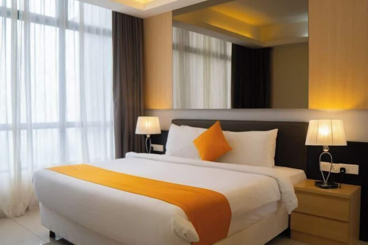 Una camera d'hotel con un letto grande, due abat-jour, un comodino e una finestra con tende.