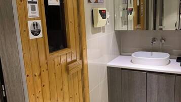 A bathroom with a wooden door, a white sink, and a mirror above it.