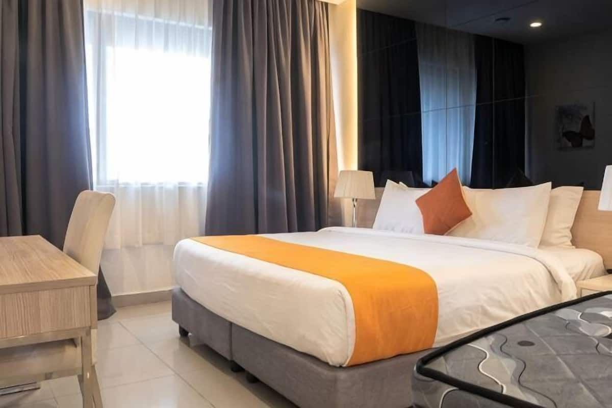 Una camera d'albergo con un letto, una scrivania, una sedia e una finestra con tende.
