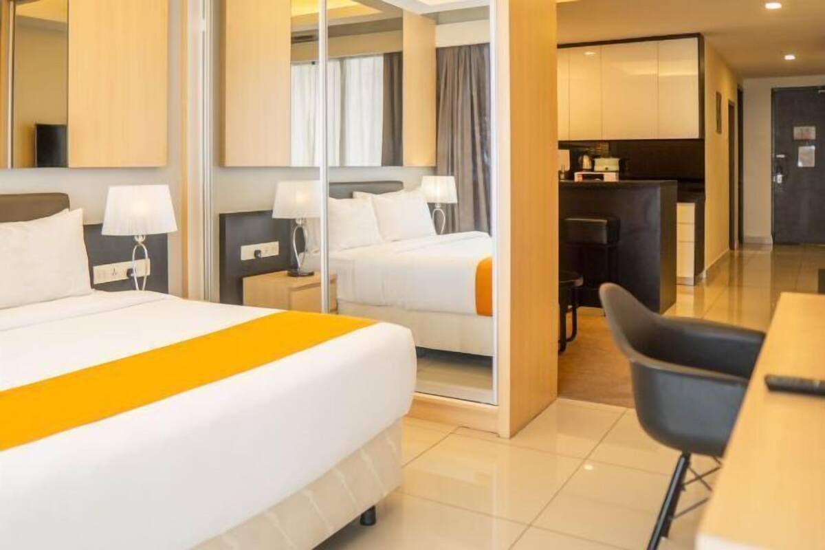 Una camera d'albergo con un letto, comodini, una scrivania e un angolo cottura.