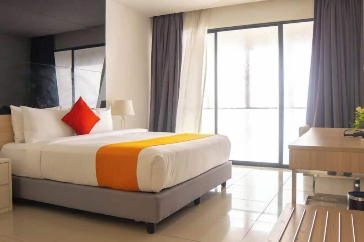 Una camera d'albergo con un letto, una scrivania e un'ampia finestra.