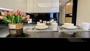 Une cuisine moderne avec des meubles blancs, un plan de travail noir et un vase de tulipes roses.