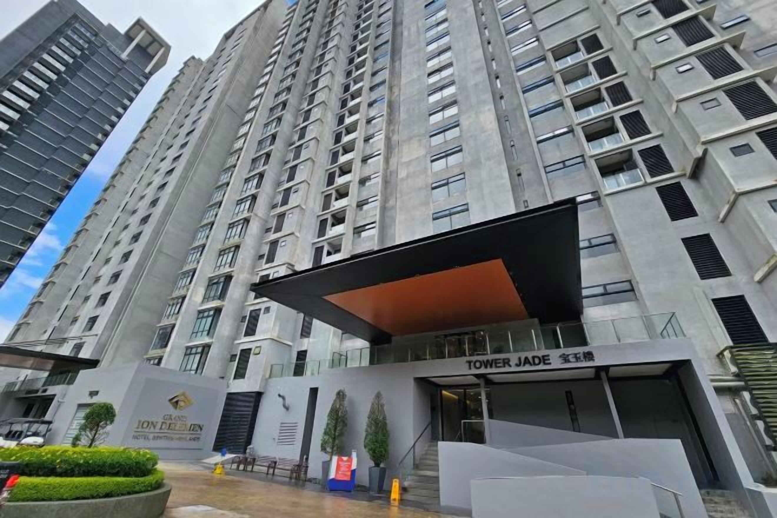 A high-rise residential building with a prominent entrance, a covered area, and a sign indicating the name 'TOWER JADE.'