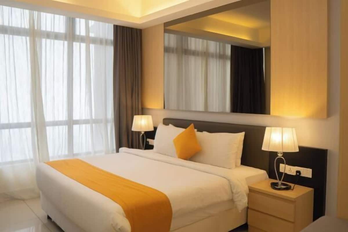 Una camera d'albergo con un letto, lampade ai comodini, un tavolino e uno specchio grande.