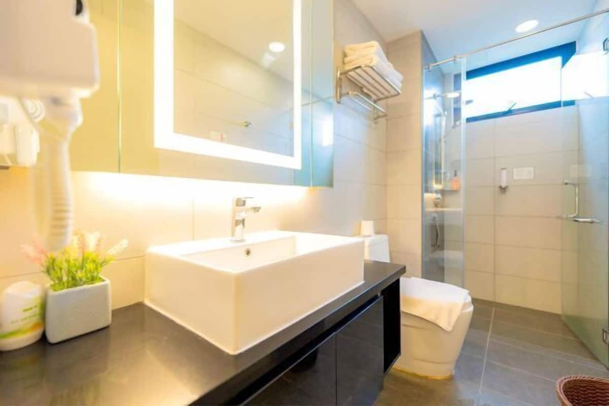 Un bagno moderno con un grande specchio, un lavandino bianco e cabina doccia in vetro.