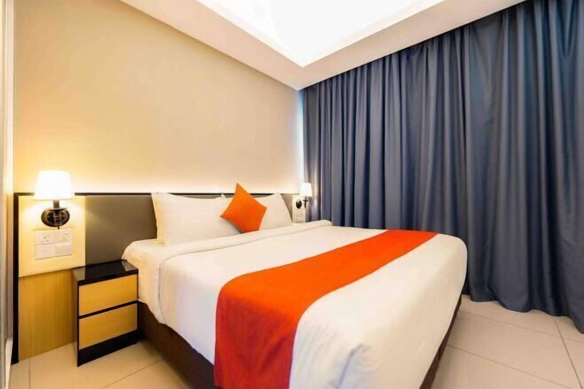 Una camera d'albergo con un letto, un comodino, una lampada e delle tende.