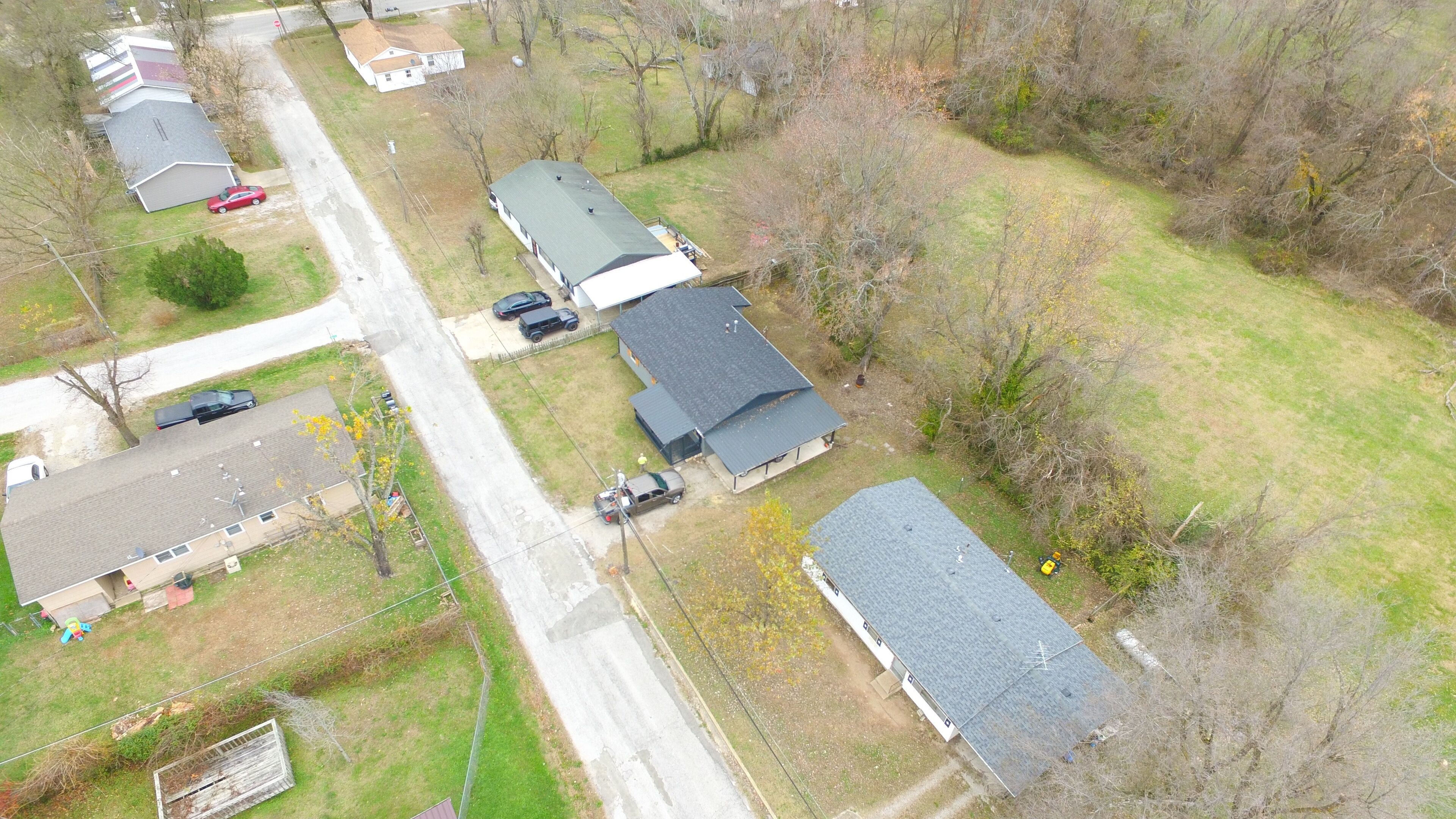 An aerial view of a residential area with multiple houses, a road, and a small body of water.