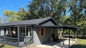 A small, single-story house with a porch and a covered patio area. - Snuggle up and relax with the whole family at this Ava home.  (Ava)