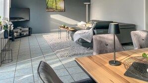 Una sala de estar moderna con un sofá gris, una mesa de centro y un televisor montado en la pared.