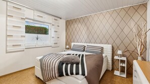 Un dormitorio con cama, ventana y vista a zonas verdes.