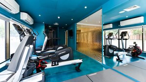 Ein Fitnessraum mit Laufbändern, Crosstrainern und einer Spiegelwand.