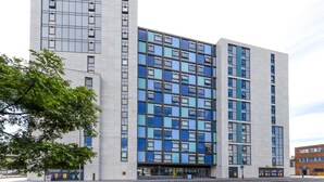 Ein modernes, mehrgeschossiges Gebäude mit einer Fensterreihung und einer glatten Fassade.