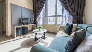A modern living room with a sofa, a small round table, a TV, and a window with curtains. - Amber Cove Premier Suites Melaka (Melaka)